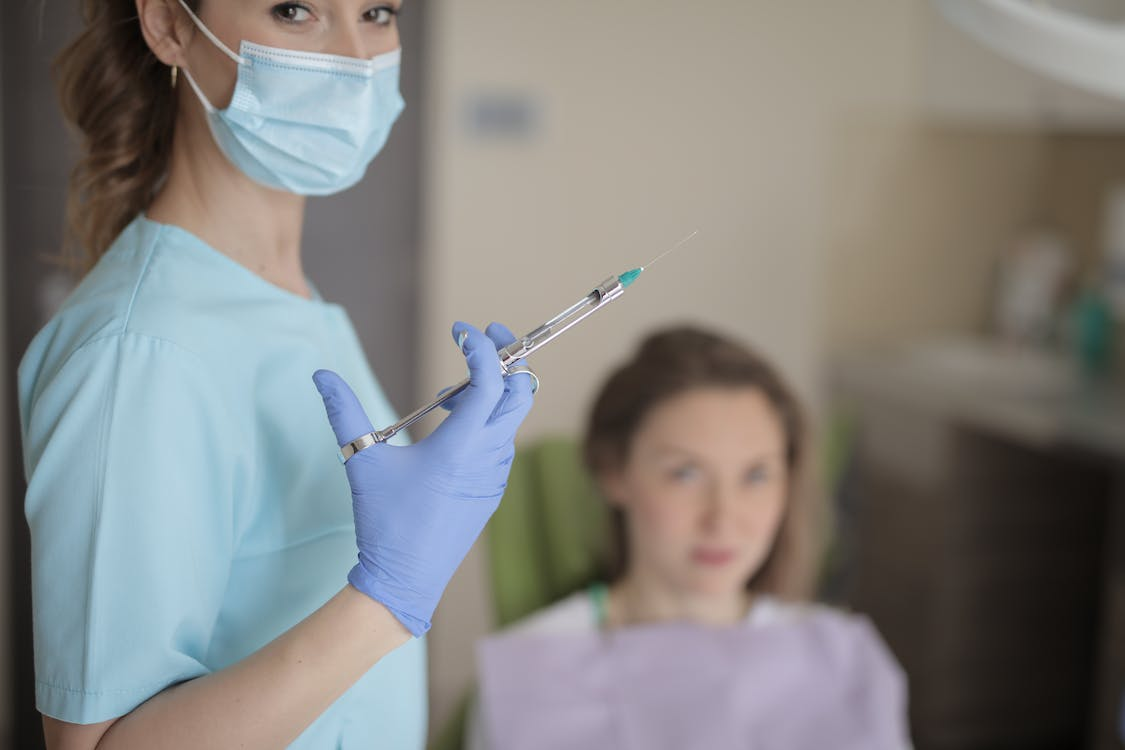 Young female dentist holding syringe in hand