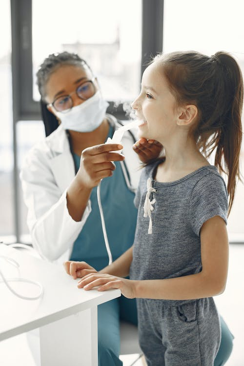 An image of a doctor giving a girl medication through a nebulizer 
