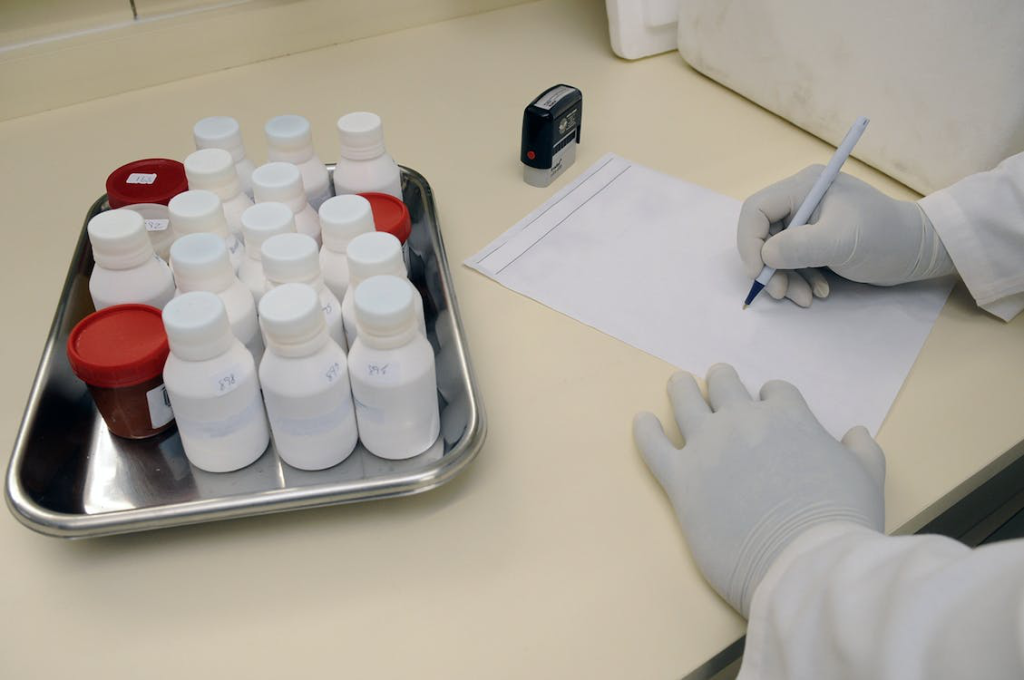 Healthcare professional writing on a paper placed next to a tray of medicine