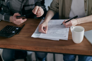 two people working together, one holding a document and the other person holding a phone