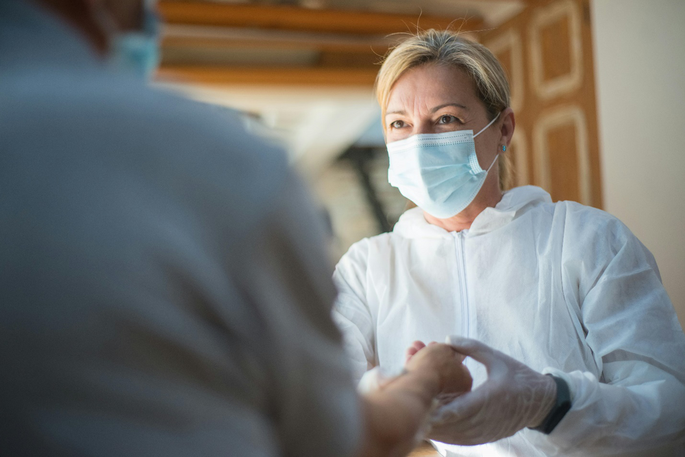 a doctor wearing a face mask and holding a person’s hand 