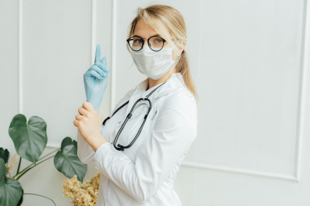 a female doctor with gloves and a stethoscope around her neck 