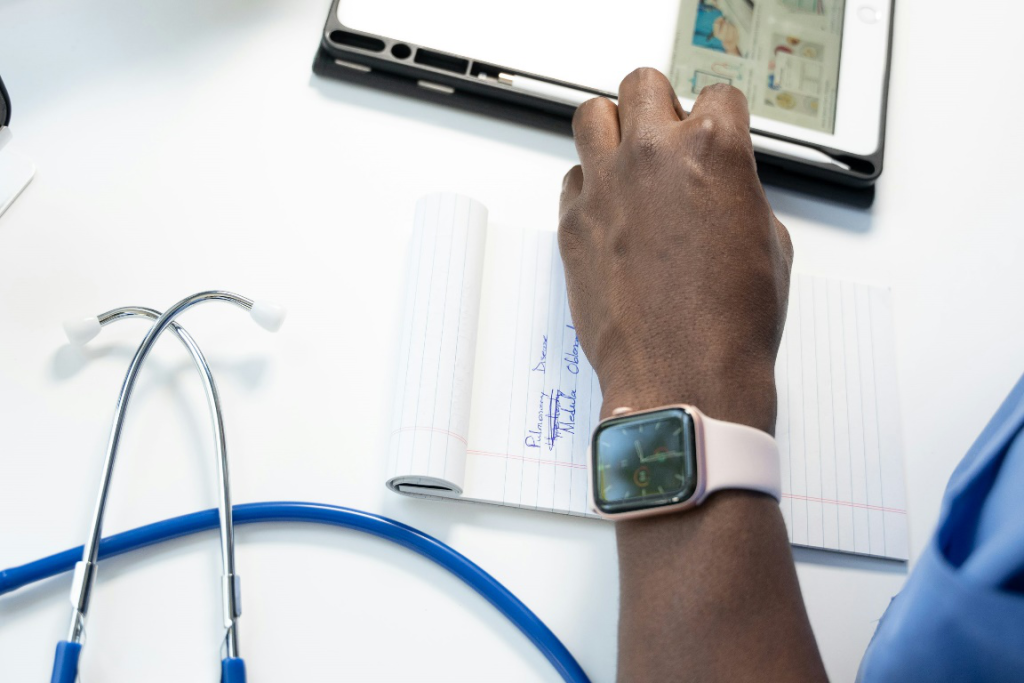 Stethoscope, tablet, and notepad arranged together on a flat surface.