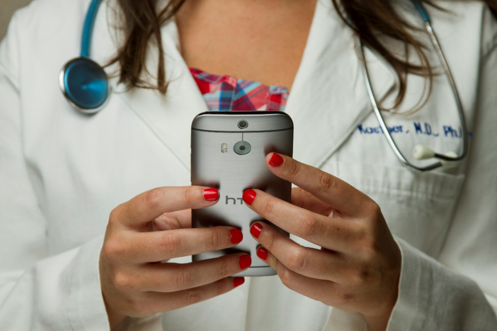 A doctor holding a smartphone while wearing a stethoscope