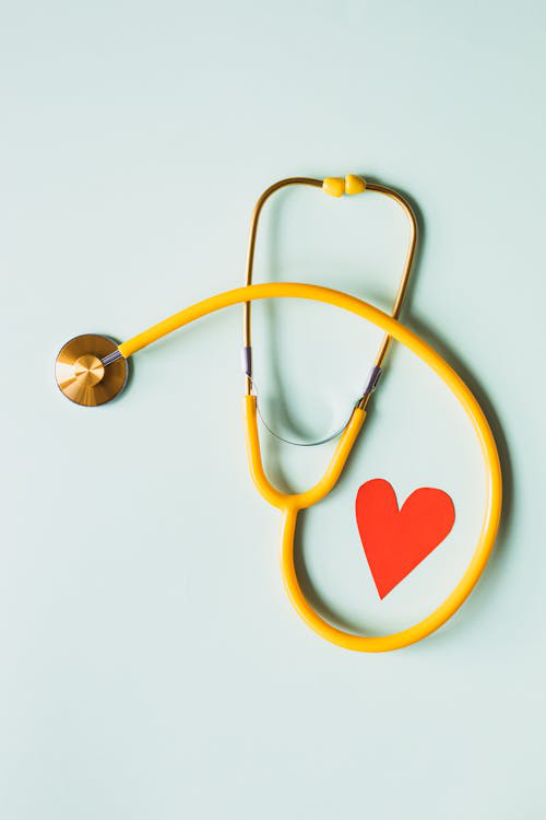 A stethoscope placed next to a red paper heart.